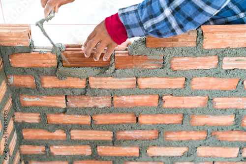 Construction worker build home by use cement mortar  to lay brick wall with a trowel follow vertical and horizontal guid line