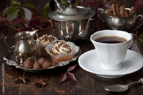 Tea with cakes and chocolate sweets on a vintage wooden background. Autumn concept. Selective focus, close-up