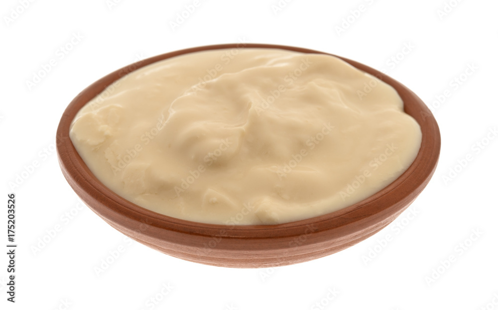 Side view of a small bowl filled with caramel yogurt isolated on a white background.