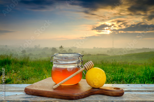 Alternative Medicine with lemon and honey on wooden table. Beautiful sunrise as background.
