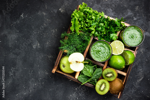 Green smoothie with ingredients on dark concrete table. Healthy  smoothie cocktail with fruits, vegetables and hebs. Healthy food and diet concept. Top view, copy space