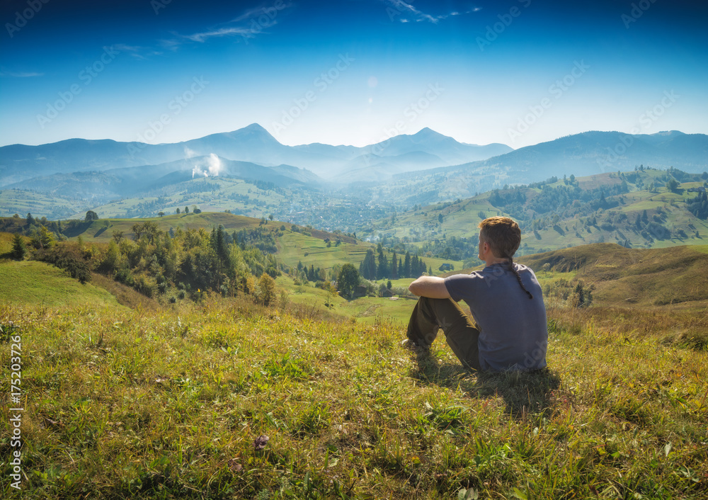 Man is sitting on a hill and enjoy the valley