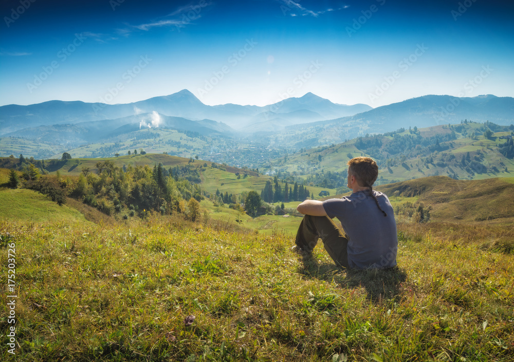 Man is sitting on a hill and enjoy the valley Man is sitting on a hill and enjoy the valley