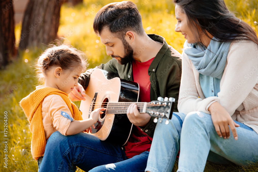 Young man playing guitar with family