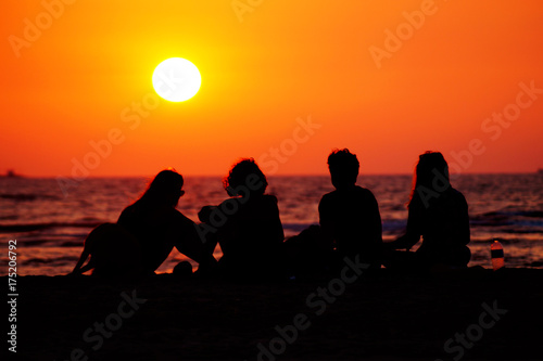Group of friends on the beach. Happy moments of life. People silhouette on the sunset.