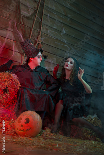 Halloween male sorcerer and woman witch, skull, pumpkin, straw, horror photo