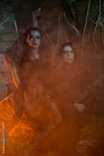 Halloween male sorcerer and woman witch, skull, pumpkin, straw, horror photo