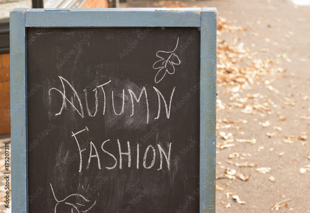 Autumn fashion - those words have written on a blackboard of vintage style on a fall street near to a shop. Welcome, autumn season!