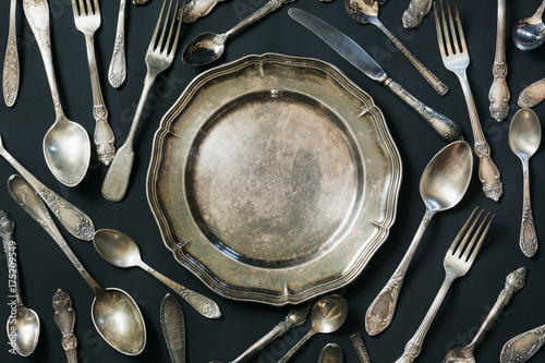 Plate, spoons, forks, knives, silverware pattern on black background. Kitchen texture.