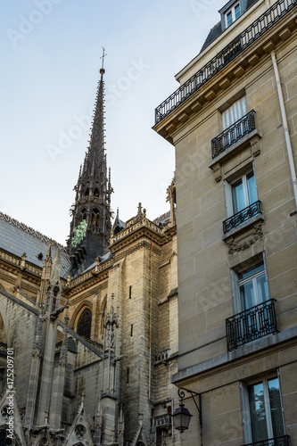 Low angle view of the spire of Notre-Dame de Paris cathedral at sunset with a residential building in the foreground.