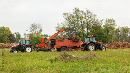 caricamento del letame su un trattore arancione su campo verde