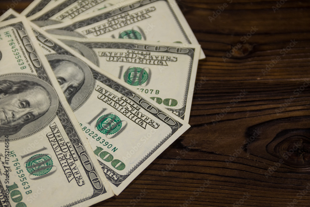 One hundred dollars bills on wooden desk One hundred dollars bills on wooden desk