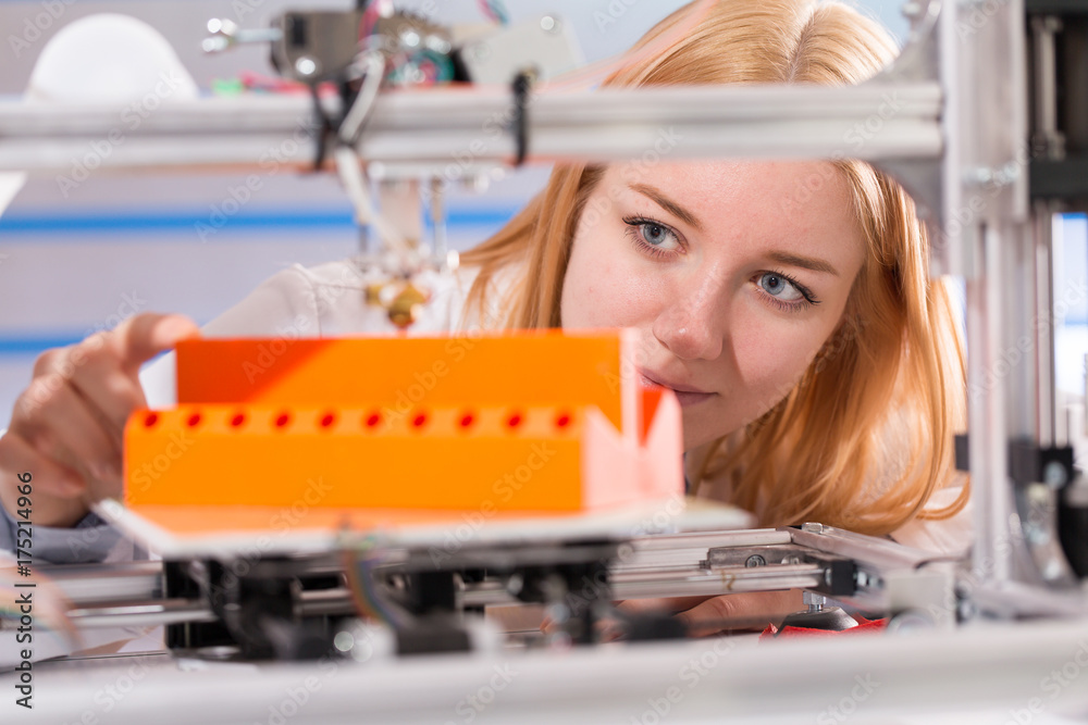 A female student or laboratory assistant in the automation laboratory is debugging the work of the 3d printer. 3d printer is a device for modeling 3D objects A female student or laboratory assistant in the automation laboratory is debugging the work of the 3d printer. 3d printer is a device for modeling 3D objects