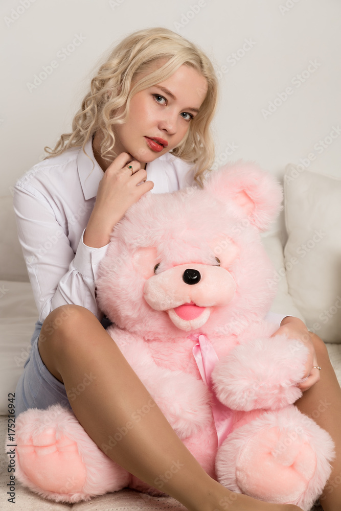 Happy beautiful blonde woman hugging a teddy bear. Concept of holiday or birthday Happy beautiful blonde woman hugging a teddy bear. Concept of holiday or birthday