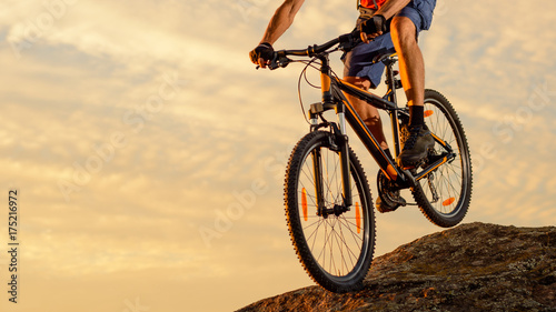 Cyclist Riding the Bike Down the Rock at Sunset. Extreme Sport and Enduro Biking Concept.