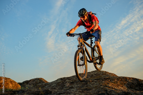 Cyclist in Red Riding the Bike Down the Rock on the Blue Sky Background. Extreme Sport and Enduro Biking Concept.