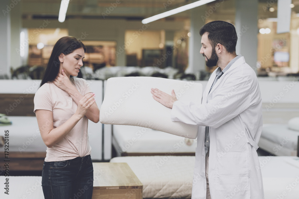 Orthopedic consultant helps a woman choose an orthopedic pillow. He shows her one of the pillow options Orthopedic consultant helps a woman choose an orthopedic pillow. He shows her one of the pillow options