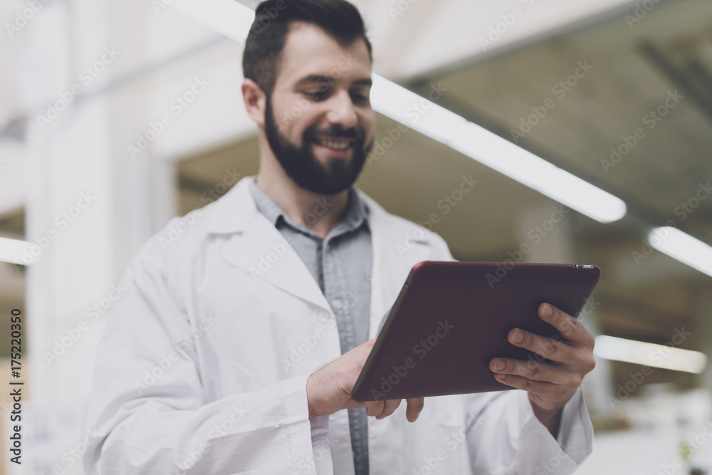A male orthopedic pose against the background of a large store of beds. He holds tablet in his hands and looks at him. A male orthopedic pose against the background of a large store of beds. He holds tablet in his hands and looks at him.