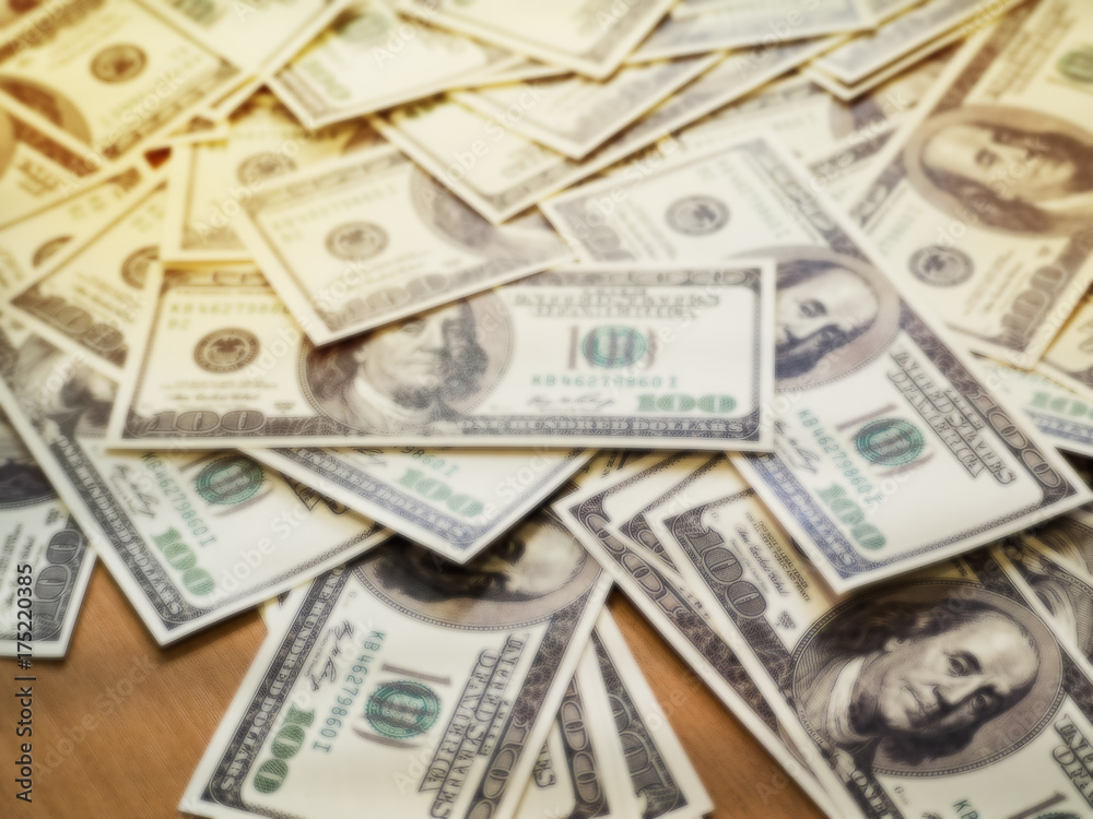 The blurry light design background of Us Dollars money on wooden desk,vintage tone. The blurry light design background of Us Dollars money on wooden desk,vintage tone.