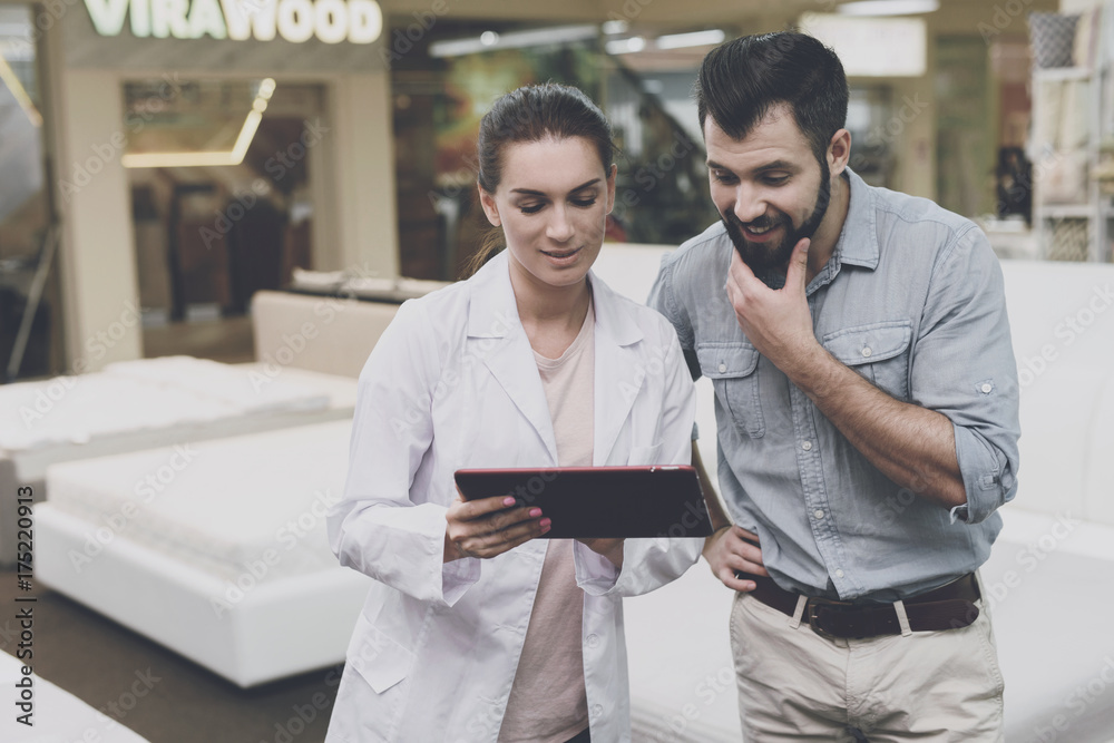 An orthopedist woman advises a man in a mattress and bed store