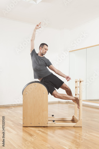 Pilates instructor performing exercise on barrel equipment