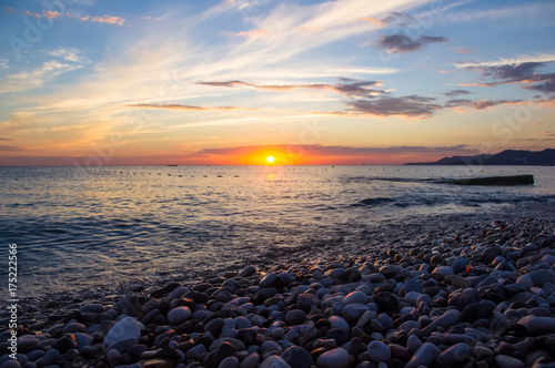 Amazing sea sunset on the pebble beach, the sun, waves, clouds © Wingedbull