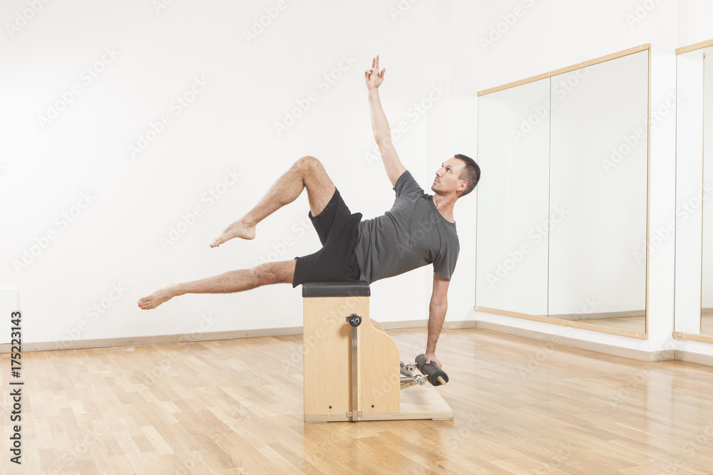 Naklejka premium Pilates instructor performing fitness exercise on chair equipment