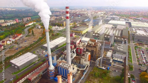 Camera flight over a modern combined heat and power plant. Fuming chimney with sulphur removal unit. Heavy industry from above. Power and fuel generation in European Union. 