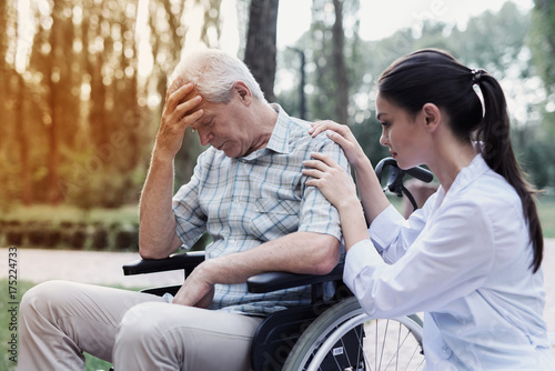 The doctor calms the dejected old man in a wheelchair © VadimGuzhva