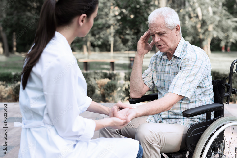 An elderly man in a wheelchair complains of a headache to a doctor