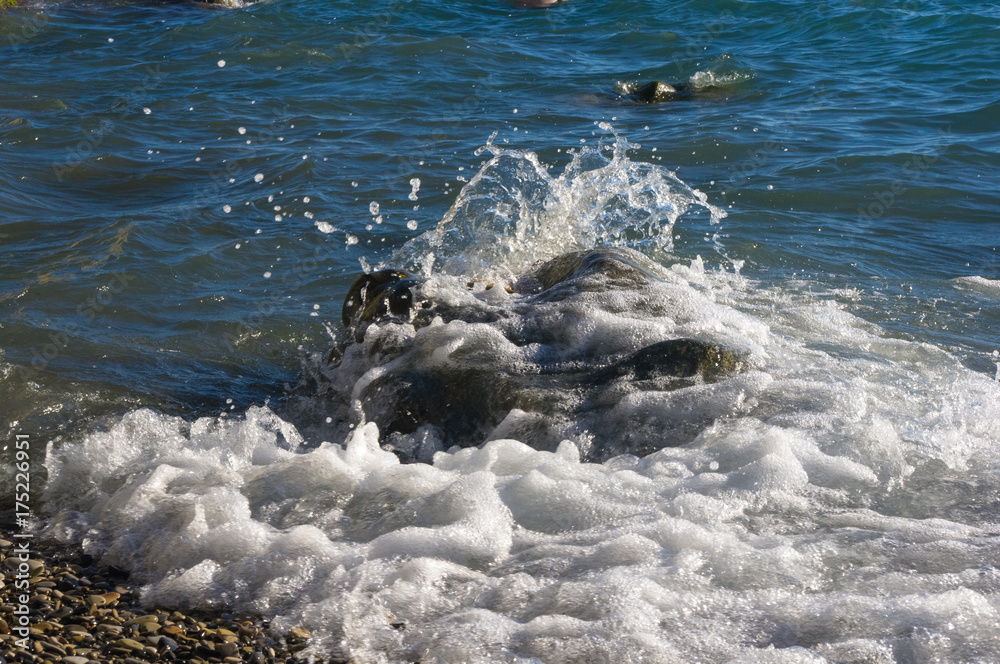 rocky sea shore with pebble beach, waves with foam