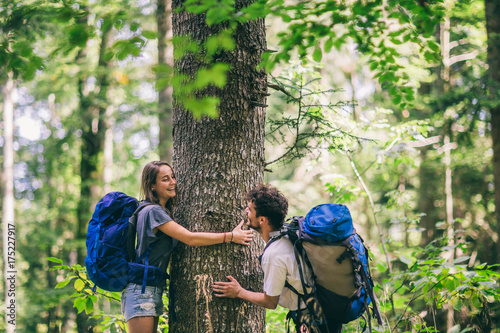 Hiking couple. Young couple with backpacks hugging tree and having fun  © Astarot