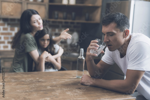 Εκτύπωση καμβά A man sits at a table and drinks, while a wife and daughter are sitting next to