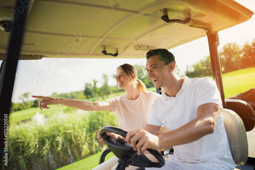 Couple riding a white golf cart on the golf course