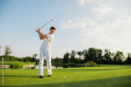 An athlete in a white suit took a golf club to strike