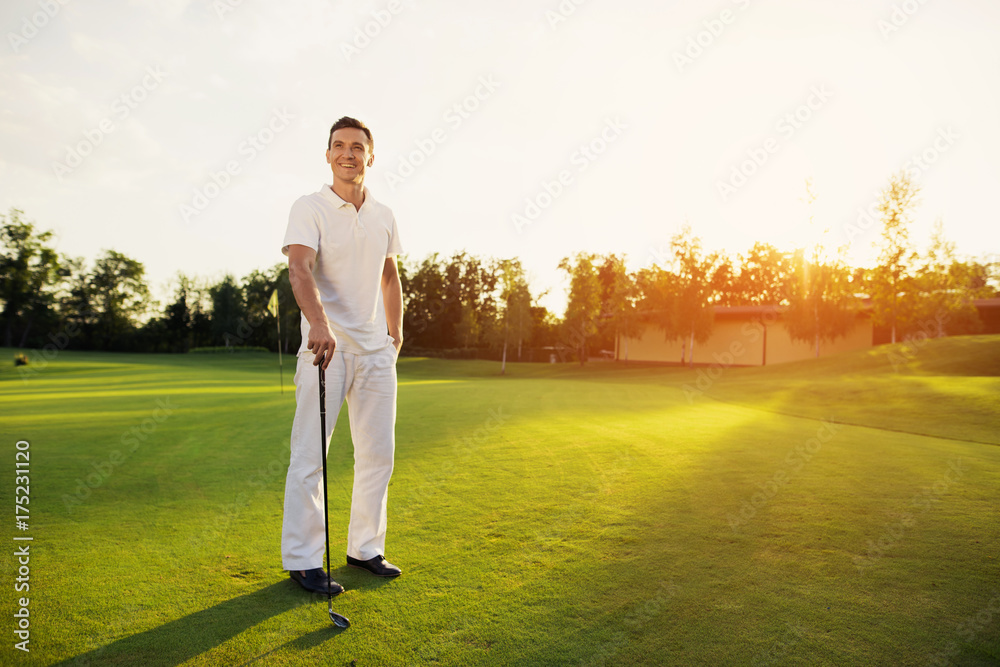 A professional golfer. A man is posing on a golf course with a stick in his hand