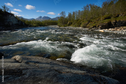 Landscape with turbulent river and blue sky