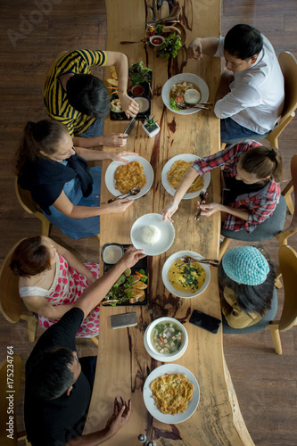 Enjoying dinner with friends. Top view of group of people having dinner together while sitting at the rustic wooden table/Group Of People Dining Concept