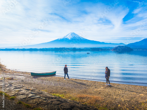 silhouette asia couple traveler 30s to 40s , boy walk to his girlfriend and take picture with boat on ground at side of lake kawaguchi on morning time with fuji mountain background
