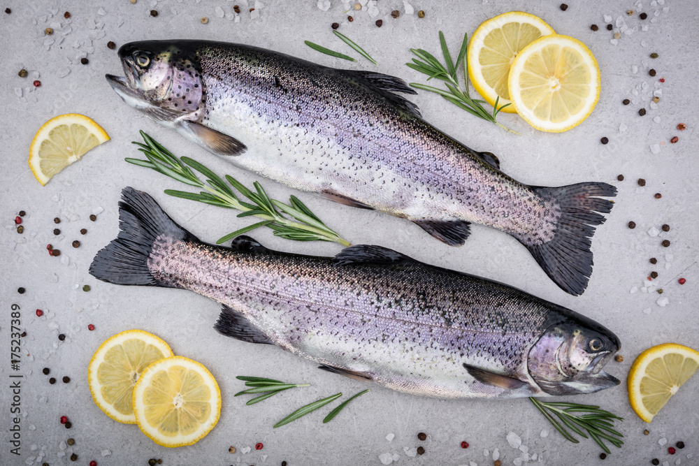 Fresh fish. Trout with salt, lemon and spices on gray background. Cooking fish with herbs. Top view Fresh fish. Trout with salt, lemon and spices on gray background. Cooking fish with herbs. Top view