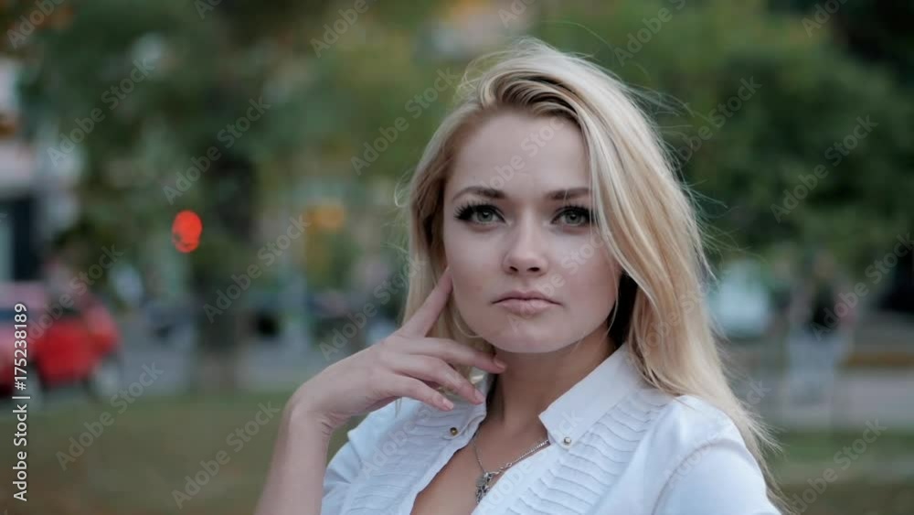 Portrait of young happy blonde businesswoman in the city. Slow motion. Beautiful girl in white sexy shirt turns around and smiles in the street. Fluttering hair. Portrait of young happy blonde businesswoman in the city. Slow motion. Beautiful girl in white sexy shirt turns around and smiles in the street. Fluttering hair.