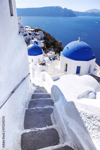Santorini Island, the city of Oia, Greece. Traditional Greek architecture, white houses and churches with blue domes above Caldera, Aegean Sea.