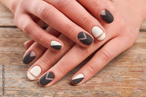 Female hands with stylish manicure. Woman hands with black and white matte manicure on old wooden background close up. Salon beauty and spa.