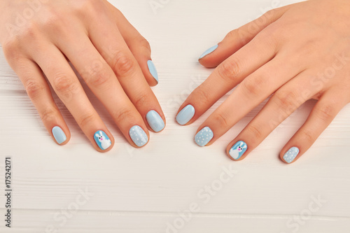 Winter design manicure on female hands. Well-groomed woman hands with gentle manicure. Young woman manicured hands on white wooden background.