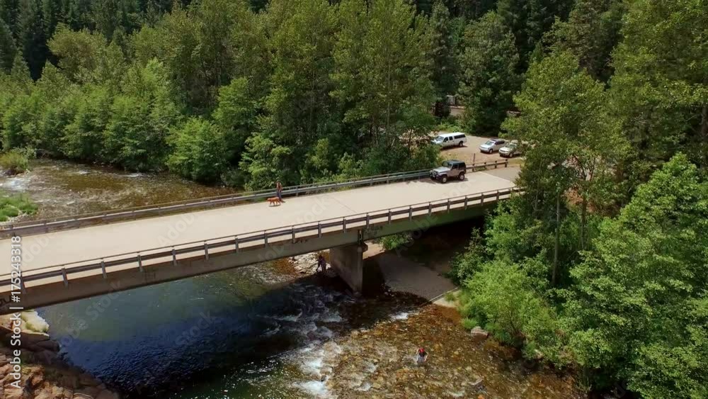 People fishing on a small mountain strweam near a bridge People fishing on a small mountain strweam near a bridge
