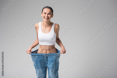 Excited young woman wearing oversized jeans after fitness