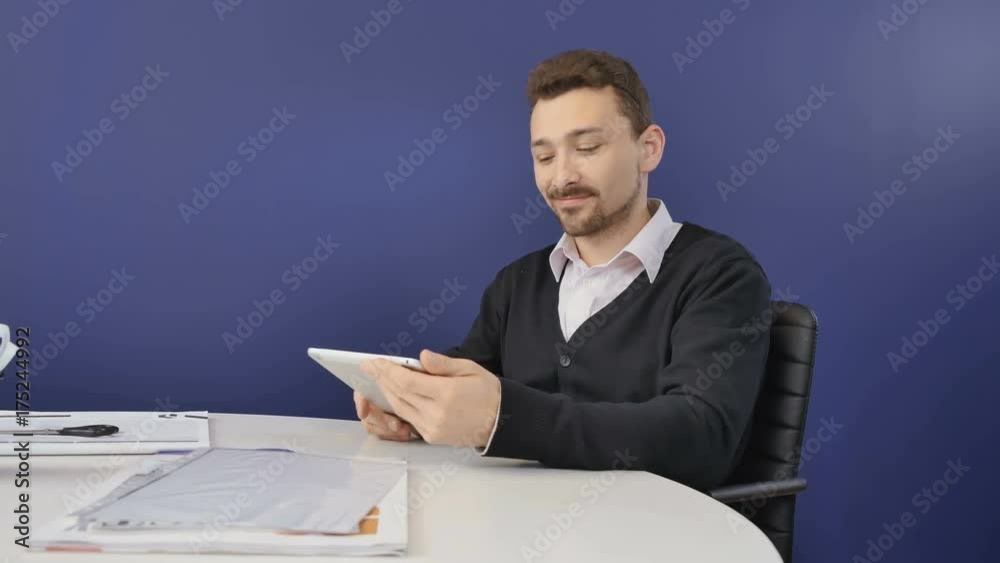 Smiling boss works with tablet in the office Smiling boss works with tablet in the office