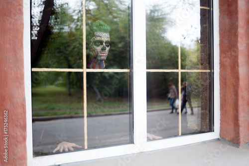 View of man with skeleton make up in the window. Halloween makeup concept  scary man in window.
