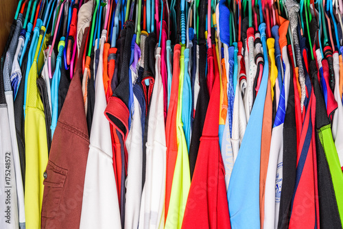 Colorful shirts or clothes are hung in the closet.