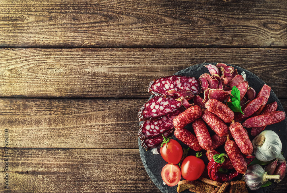 Food tray with delicious salami, pieces of sliced ham, sausage, tomatoes, salad and vegetable.